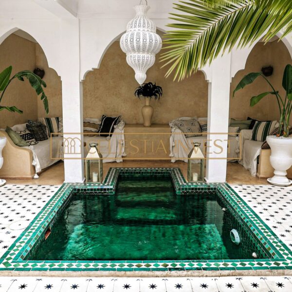 Patio del Riad con piscina de mosaico verde, rodeada de azulejos estampados y plantas