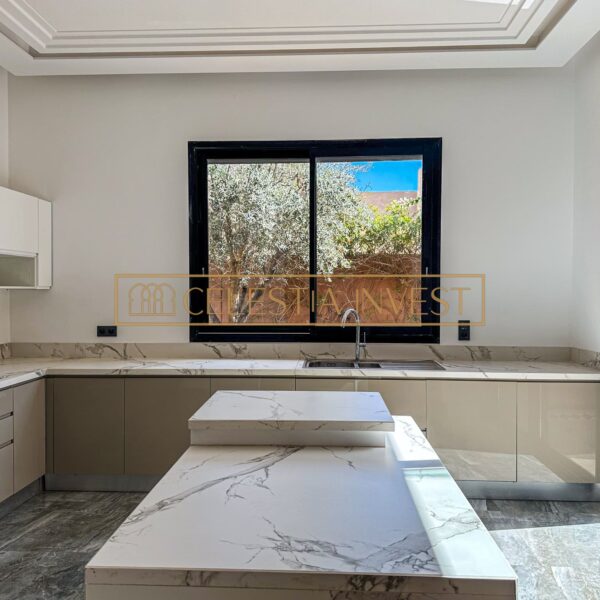 Modern kitchen with marble center island and garden view.