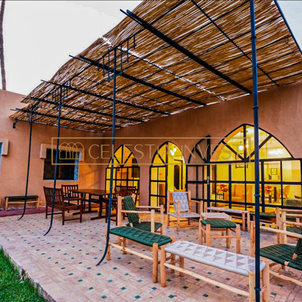 Refrescante zona de descanso junto a la piscina con techo de paja y cómodos asientos en una villa de lujo de Marrakech.